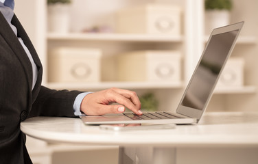 Business woman below chest working on her laptop in a cozy environment
