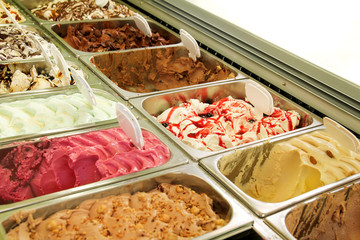 Ice cream fridge with creamy and fruit Italian ice cream steel serving counter with many of refreshing sweet scoopable flavors. Ice cream display, various flavors of gelato ice cream. Pastry shop.