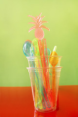 Colorful plastic spoon and plastic spatula tool kitchenware for ice cream in glass. Color of drinking straw. Pile of plastic colored cocktail straws to consumption of drinks.