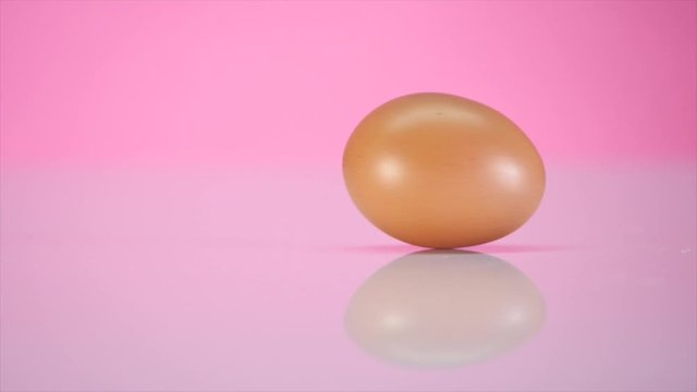 The egg spins on a table on a pink background