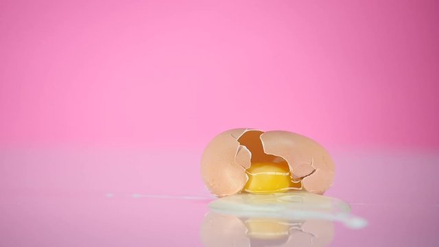 The egg falls and crashes on pink background