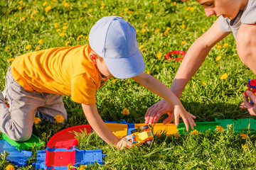two brothers plays with a toy car on the green grass lawn