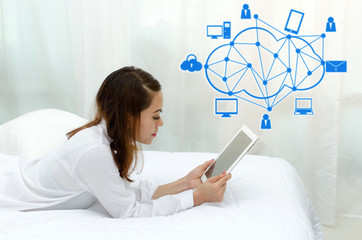 happy young asian woman in white pajamas using mobile tablet on bed in the morning at home and graphic network icon, smart communication technology, online shopping and payment online concept