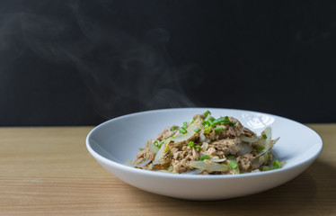 Healthy meal, stir fried tuna with onion. Close up food image with smoke. Black background.