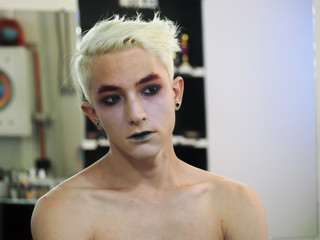 Make up artist makes make-up blond male model close-up