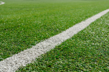 White stripe on Artificial green football soccer field from side view.