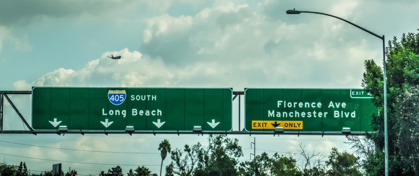 Airplane flying over 405 freeway sign in Los Angeles