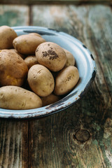 Full bowl of raw potato on a rustic background with copy space