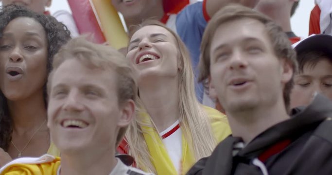 Group of enthusiastic sports fans cheering at match, slow motion