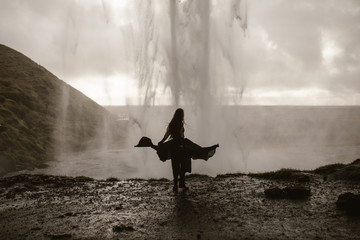 Woman wearing a black dress by a waterfall in Iceland