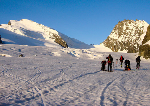 many backcountry skiers get ready to climb a high alpine peak in the Alps near Zermatt just after sunrise