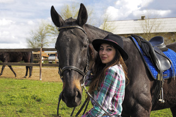 a girl is walking with a black horse in nature