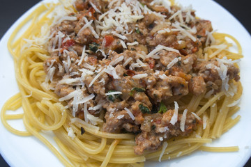 Appetizing spaghetti in a plate with Bolognese sauce on a dark background close up