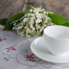 Porcelain cup and bouquet of lily of the valley
