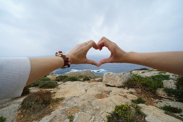 海辺で、手で作るハート
