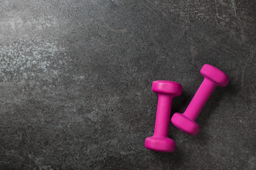 Fitness concept with pink dumbbells on black background