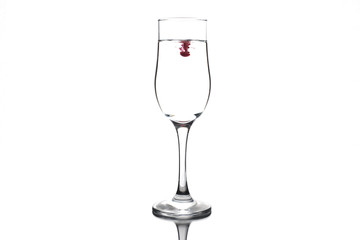 A drop of red and black liquid was just poured into a clear wineglass