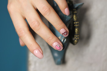 Beautiful female hand with manicure. Light pink nail polish with creative design. Lips and ice cream stickers.