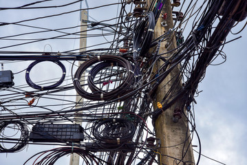 Wires on an electric pole many electrical cable and cable clutter. potential danger from a mess line on electricity post Thailand.