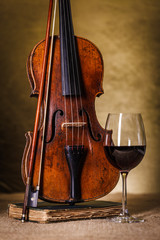 Classical old violin with red wine glass