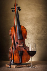 Classical old violin with red wine glass