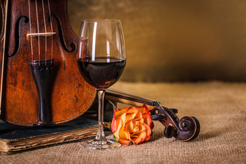 Classical old violins detail with red wine glass