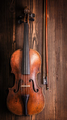 Violin with bow on wooden background