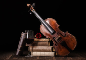 Old violin with books and red wine
