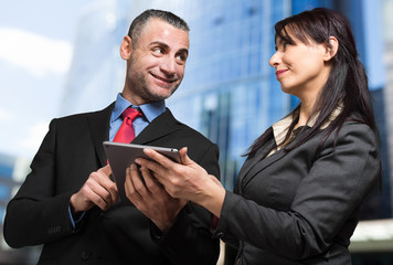 Two business partners using a digital tablet outdoor