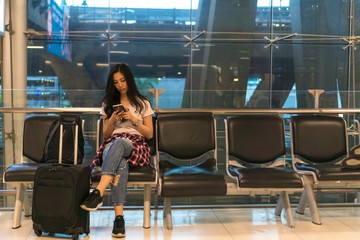 Tourist girl Living cell phone at the airport. She is waiting for a trip. For holiday travel. Copy space.