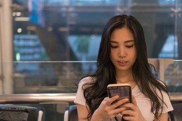 Tourist girl Living cell phone at the airport. She is waiting for a trip. For holiday travel. Copy space.