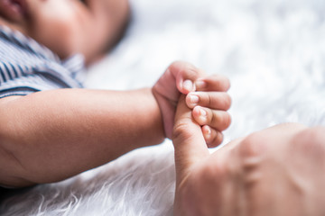 hand the sleeping baby in the hand of mother close-up. Extreme closeup of a baby's hand in mother's finger. Close-up of baby's hand holding mother's finger. tenderness.
