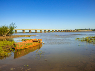 Fototapeta premium Canoe by the Uruguay river, International bridge in the background
