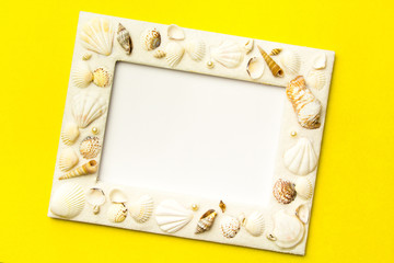 Photo frame with shells on  yellow color paper texture background. The concept of a summer vacation.  Summer Flatlay Image