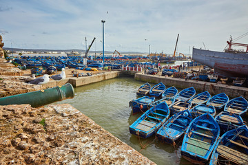 Essaouira port in Morocco with blue fishing boats and ancient famous fort on background