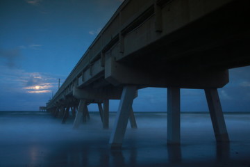 North Side of Deerfield Beach, Florida Pier at Twilight with Moonrise Partially Obscured by Clouds in a Long Time-Exposure with Foggy Cotton Candy Waves at the Base in Late October Near Halloween