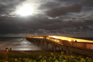 Deerfield Beach Pier Boardwalk Lit Up Illuminated Facing East toward the Atlantic Ocean at Night with a Moonrise Revealing Color in the Cloudy Sky in Late October Near Halloween