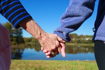 Mother and Daughter Holding Hands with Lake in Background in a Clear Sunny Day in Burke, Virginia