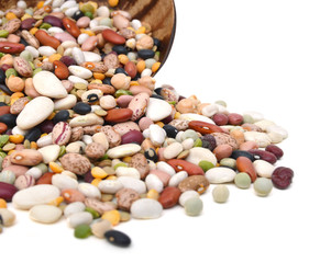 A mixture of legumes in an earthenware bowl, white background.