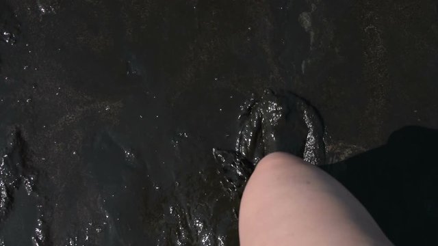 Top view of woman walking in the mud of salty-bitter lake. Healing and therapeutic mud