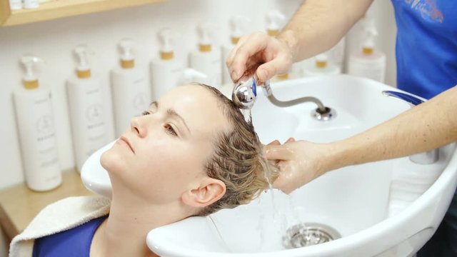 Hairdresser wash woman hair in salon sink slow mov 4K
