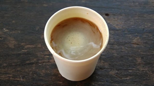 Coffee,close up.
Coffee top circling after blending in white paper cup on old wooden table, high angle view hd slow motion.

