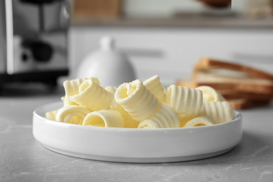 Plate with tasty butter curls on table