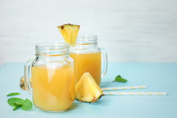 Mason jars with delicious pineapple juice on table