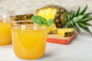 Glass with delicious pineapple juice on table