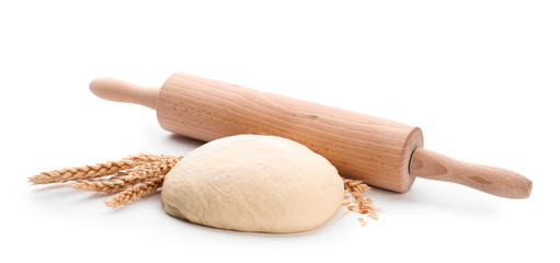 Raw dough and rolling pin on white background