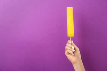 Woman holding yummy ice cream on color background. Focus on hand