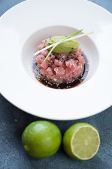 Close-up of tuna tartare in soy sauce with guacamole quenelle and green onion on top, selective focus, vertical shot