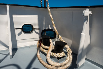 bollards with white rope on sunny ship deck