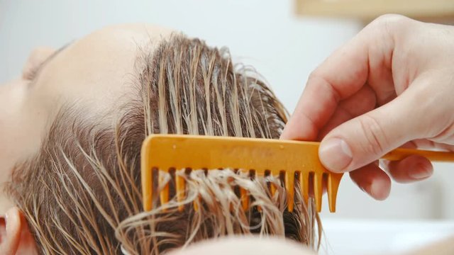 Hairdresser combing wet hair in slow motion 4K